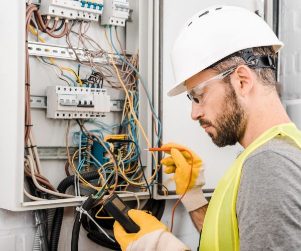 handsome-electrician-checking-electrical-box-with-multimetr-in-corridor-e1624860078476.jpg